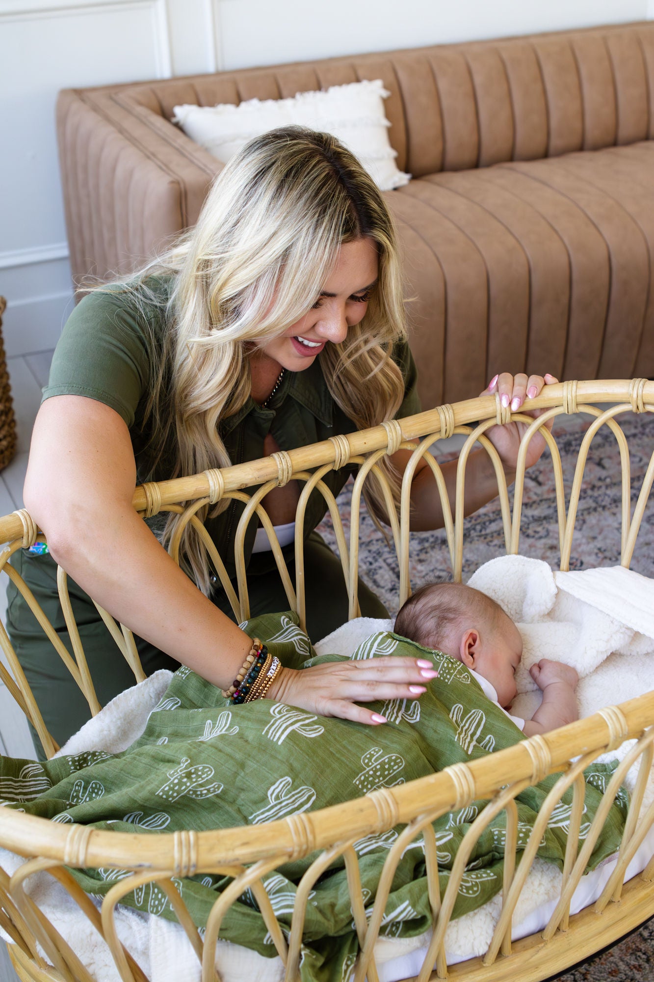Woman tending to a baby in a crib with a green blanket