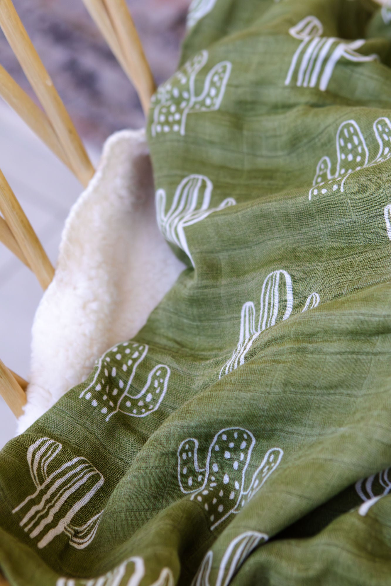Green fabric with white patterns held by a hand against a blurred background
