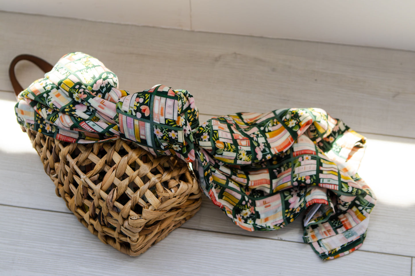 Floral-patterned fabric draped over a woven basket on a wooden floor.