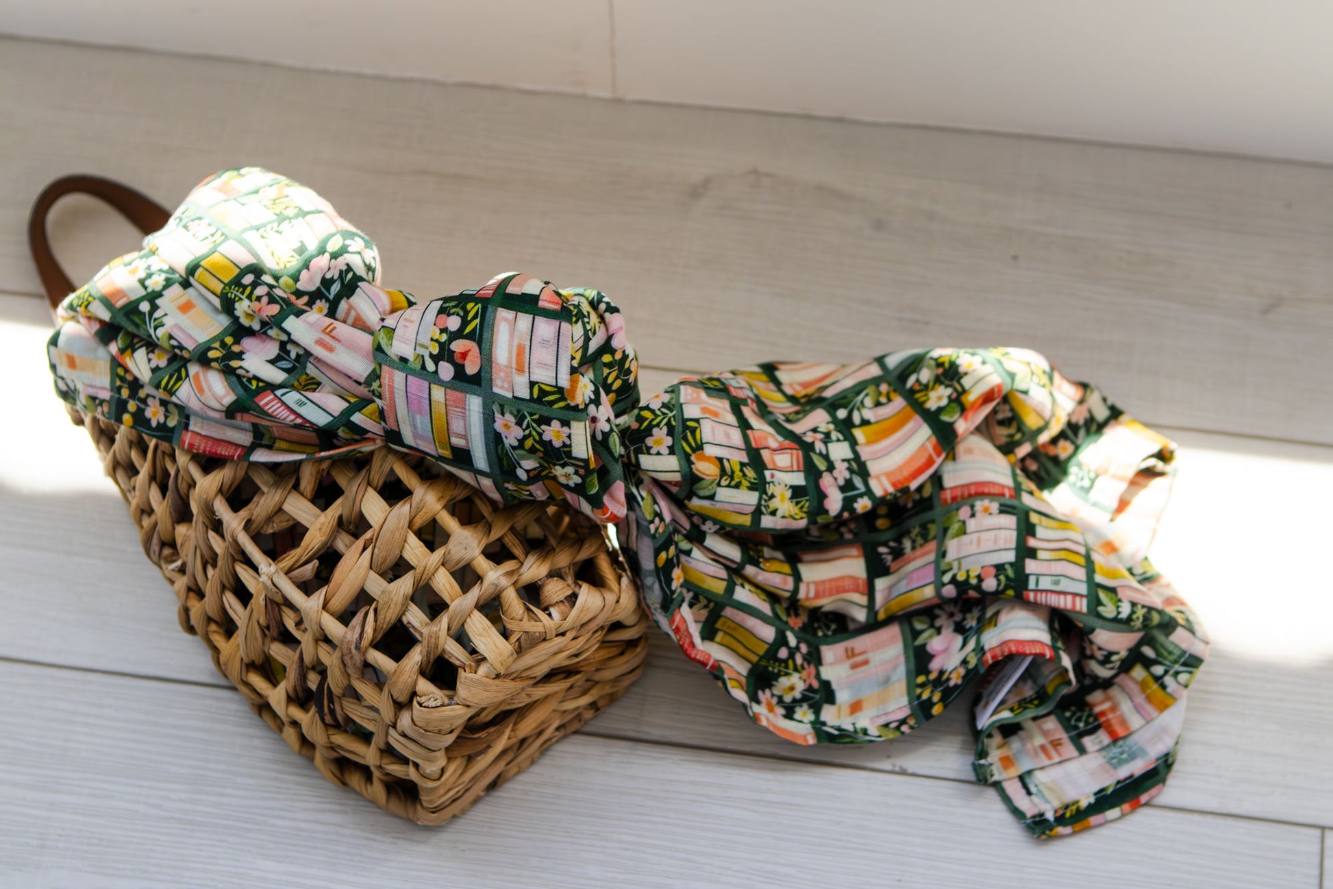 Floral-patterned fabric draped over a woven basket on a wooden floor.