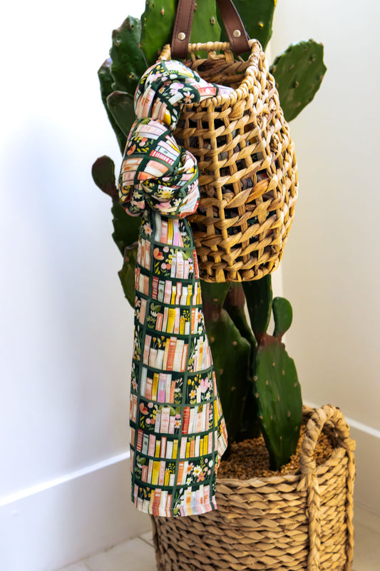 Woven basket with a patterned towel draped over it, against a white wall.